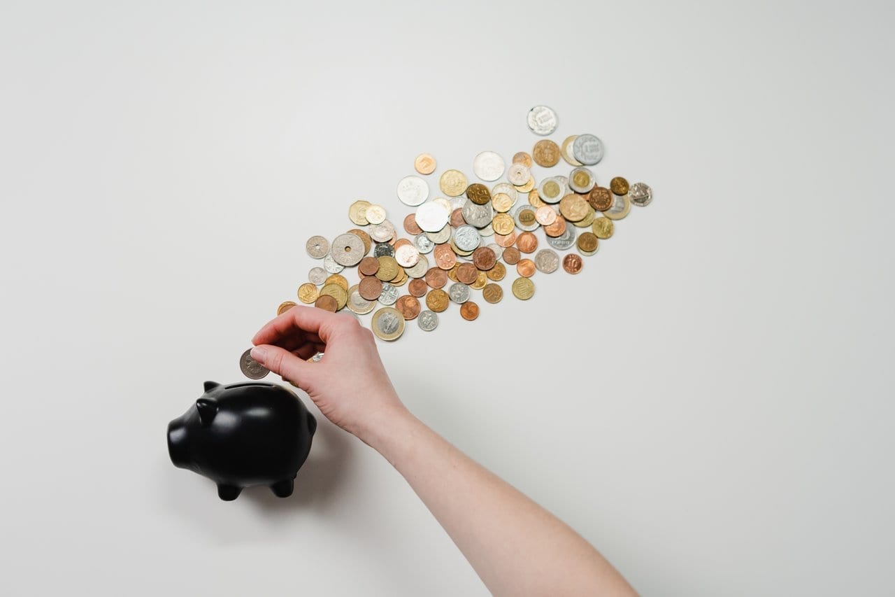 A person putting a coin in a black piggy bank