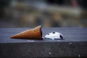 An ice cream in a cone, on the ground.