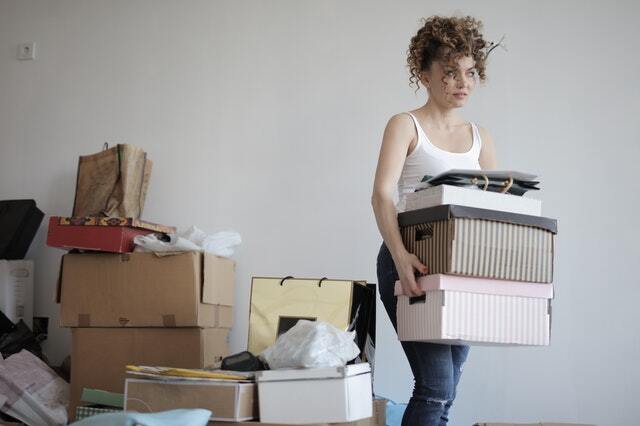 A woman carrying three boxes after decluttering her home.