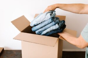 A person putting four pairs of jeans into a box.