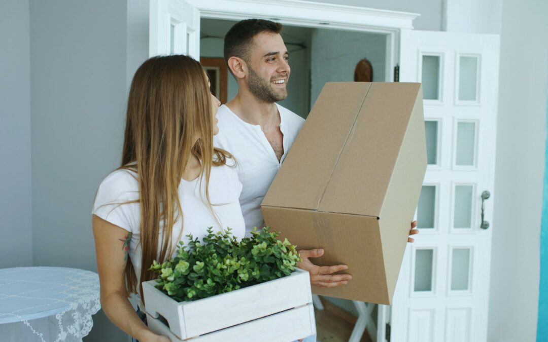 Couple carrying moving boxes into a new home